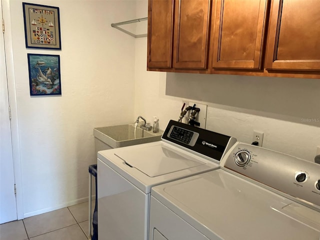 clothes washing area featuring sink, washer and clothes dryer, cabinets, and light tile floors