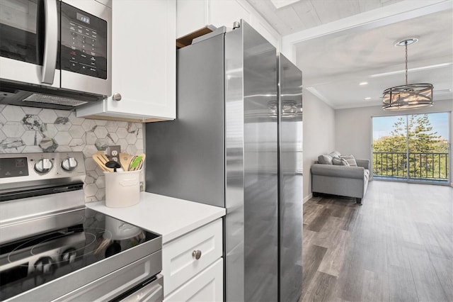 kitchen with appliances with stainless steel finishes, dark hardwood / wood-style flooring, decorative light fixtures, a notable chandelier, and white cabinets