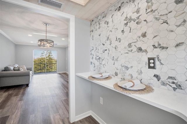 hallway featuring crown molding, dark wood-type flooring, and an inviting chandelier