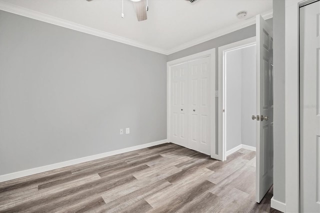 unfurnished bedroom featuring ceiling fan, light hardwood / wood-style floors, ornamental molding, and a closet