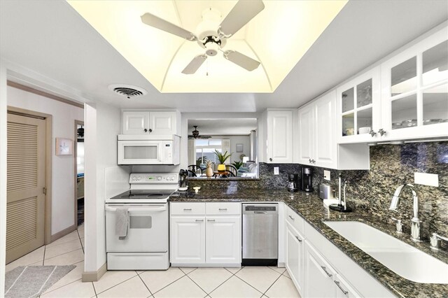 kitchen with sink, dark stone countertops, a raised ceiling, white appliances, and white cabinets