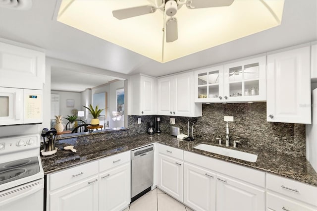 kitchen with white cabinetry, sink, white appliances, and dark stone countertops