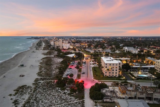 aerial view at dusk featuring a beach view and a water view