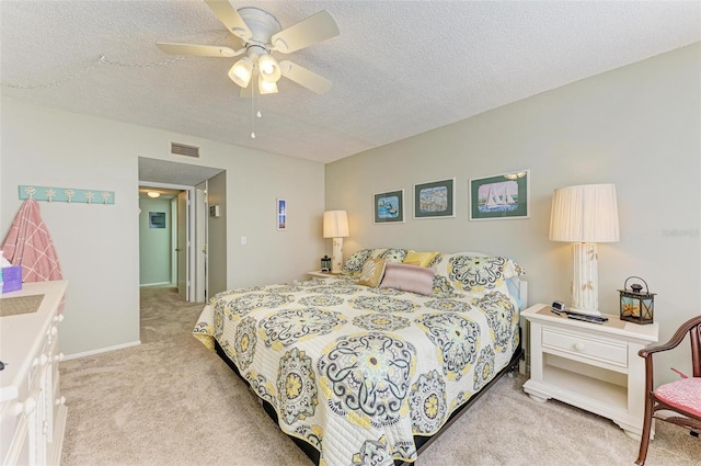 bedroom with light carpet, ceiling fan, and a textured ceiling