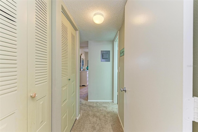 hallway with light carpet and a textured ceiling