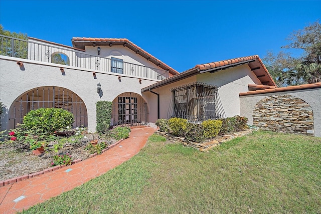 mediterranean / spanish-style home with a balcony and a front lawn