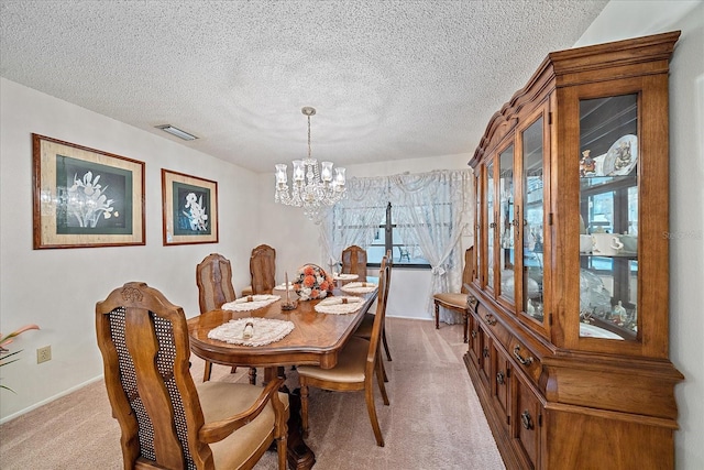 dining area with light colored carpet, a notable chandelier, and a textured ceiling