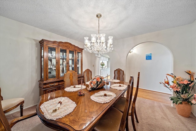 dining space featuring light carpet, a notable chandelier, and a textured ceiling