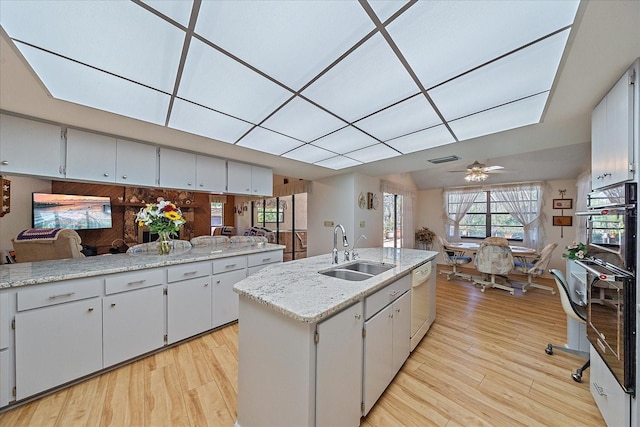 kitchen featuring sink, a kitchen island with sink, white dishwasher, and light wood-type flooring