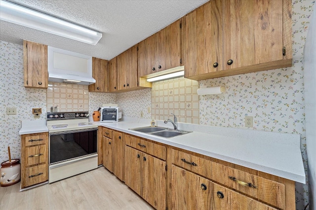 kitchen featuring sink, range with electric stovetop, light hardwood / wood-style floors, a textured ceiling, and custom exhaust hood