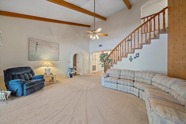 carpeted living room with a high ceiling, ceiling fan, and beam ceiling