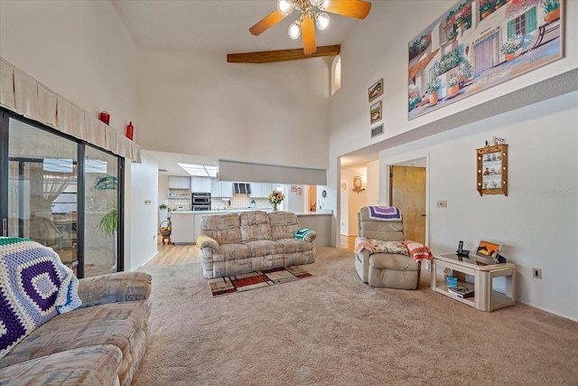 living room with ceiling fan, beam ceiling, light carpet, and a towering ceiling