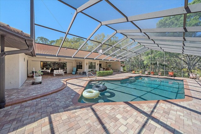 view of swimming pool featuring a patio, outdoor lounge area, and glass enclosure