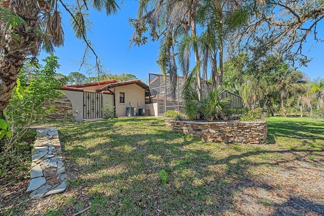 view of yard with a lanai and central AC unit