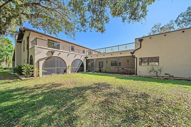 back of house featuring a yard and a balcony