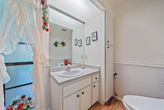 bathroom featuring vanity, toilet, and hardwood / wood-style floors