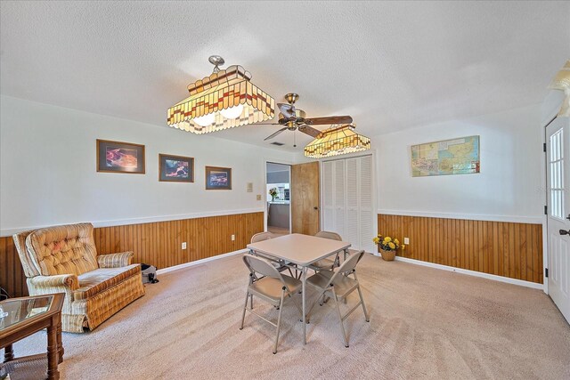 dining room with wood walls, a textured ceiling, and carpet flooring