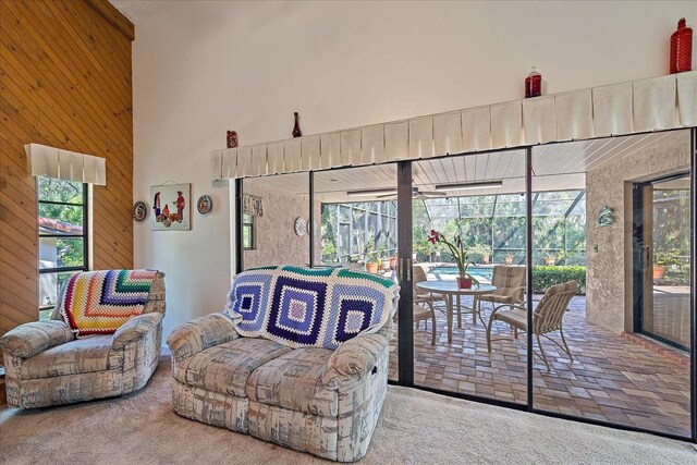 carpeted living room with wood walls, a towering ceiling, and a wealth of natural light