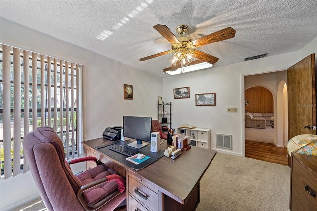 carpeted office space with ceiling fan and a textured ceiling