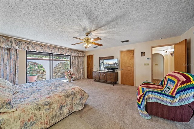 carpeted bedroom with ceiling fan and a textured ceiling