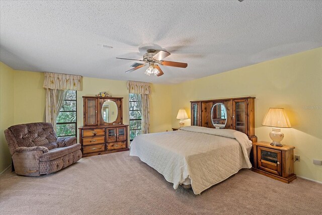 bedroom with ceiling fan, carpet floors, and a textured ceiling