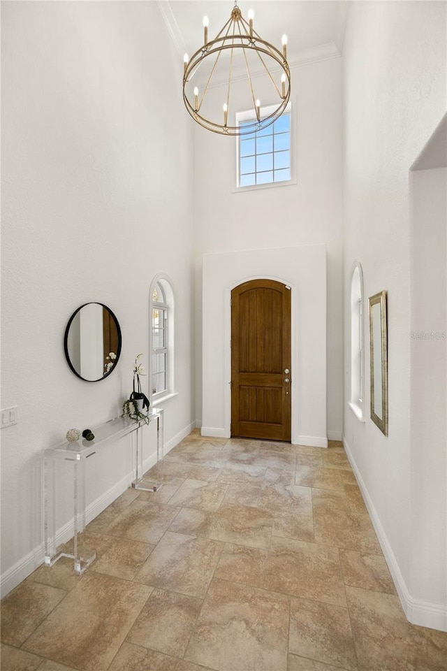 foyer with a healthy amount of sunlight, crown molding, a high ceiling, and an inviting chandelier