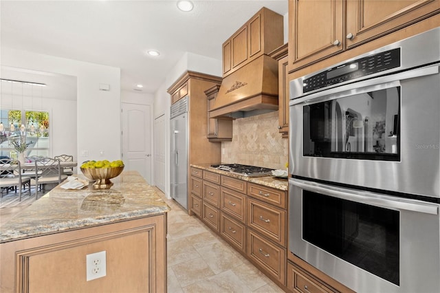 kitchen featuring premium range hood, decorative backsplash, light stone countertops, and appliances with stainless steel finishes