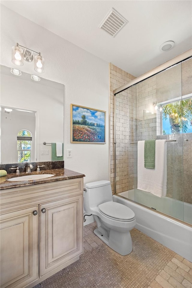 full bathroom with shower / bath combination with glass door, vanity, and toilet