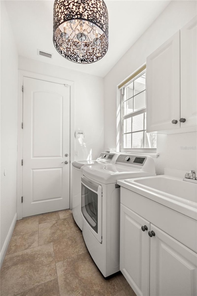 clothes washing area featuring cabinets, sink, and washer and dryer