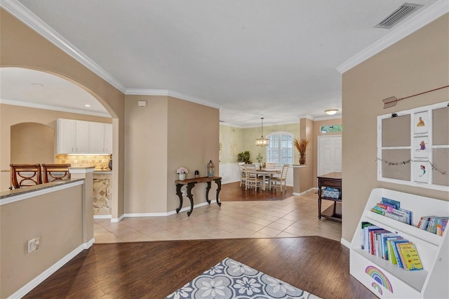 living room with crown molding, an inviting chandelier, and light hardwood / wood-style floors