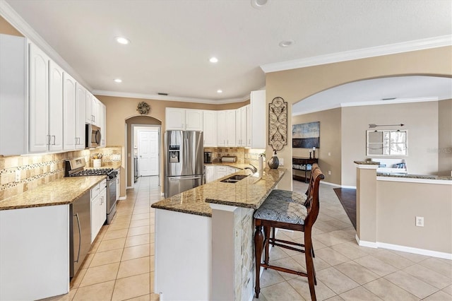 kitchen with appliances with stainless steel finishes, dark stone countertops, sink, and tasteful backsplash