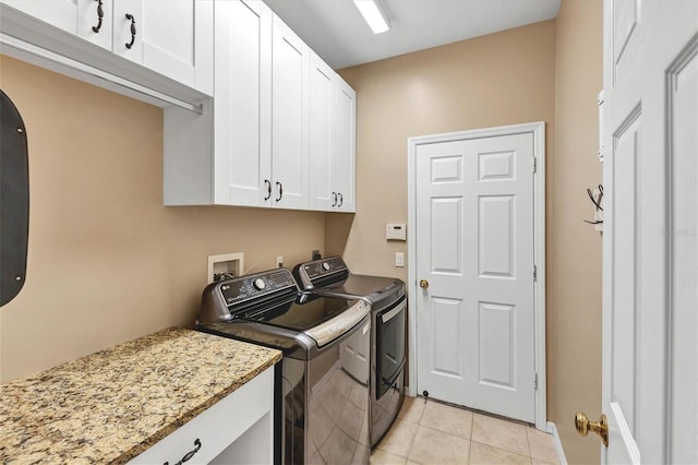 laundry area with light tile patterned floors, washing machine and dryer, and cabinets