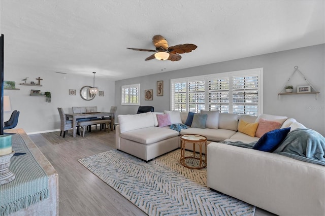 living room featuring ceiling fan with notable chandelier and light wood-type flooring