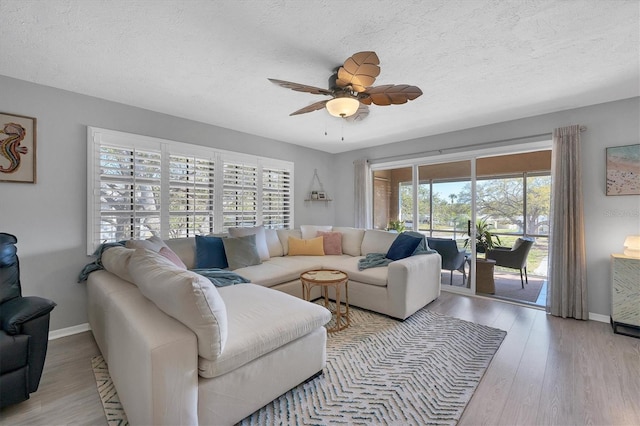 living room featuring a textured ceiling, ceiling fan, and light wood-type flooring