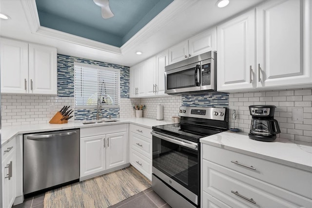 kitchen with white cabinetry, backsplash, appliances with stainless steel finishes, sink, and a raised ceiling