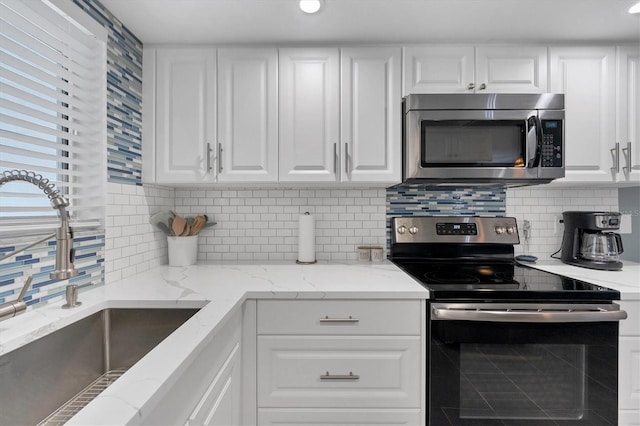 kitchen with light stone countertops, appliances with stainless steel finishes, and white cabinetry