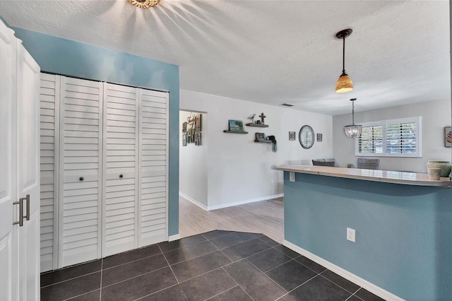 kitchen featuring hanging light fixtures, a textured ceiling, and dark tile flooring