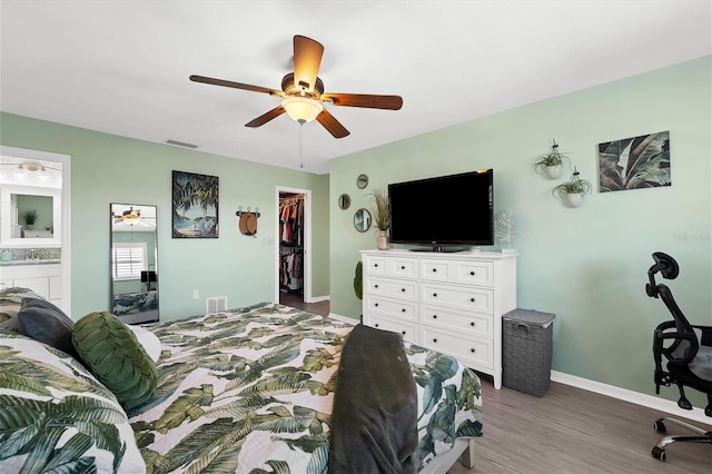 bedroom featuring ceiling fan, a walk in closet, dark hardwood / wood-style flooring, ensuite bath, and a closet