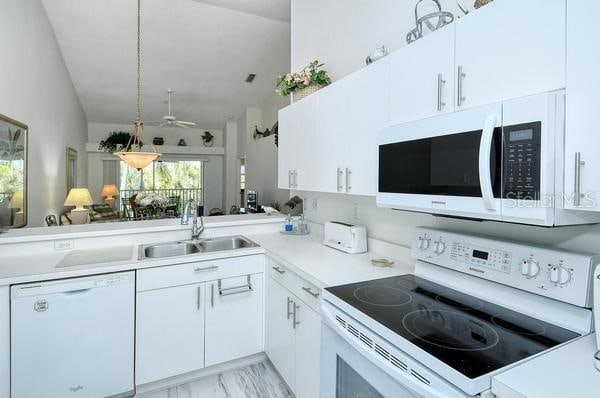 kitchen featuring white cabinetry, sink, kitchen peninsula, vaulted ceiling, and white appliances