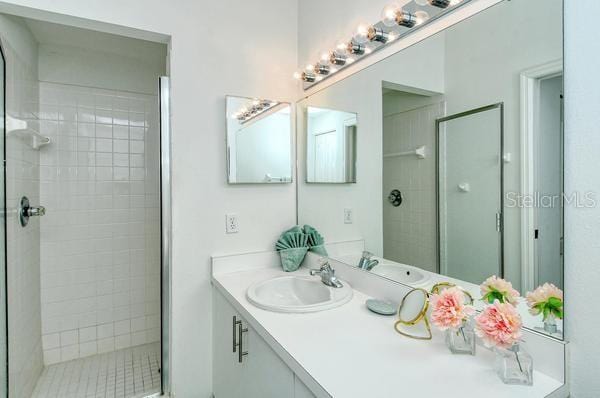 bathroom featuring a shower with door and vanity