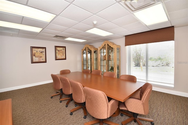 dining space featuring a drop ceiling and dark carpet