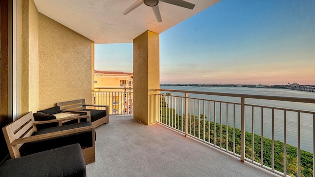 balcony at dusk with a ceiling fan and a water view