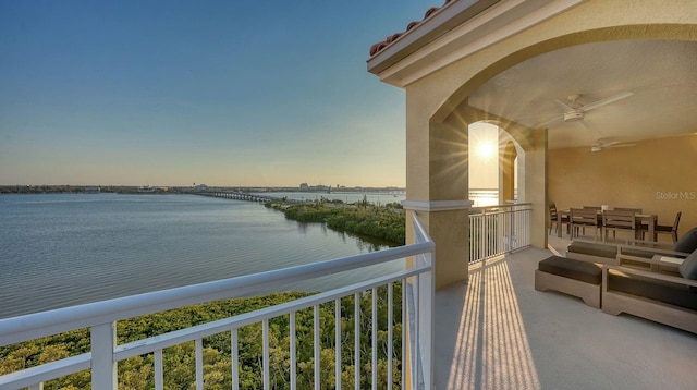 balcony with ceiling fan and a water view