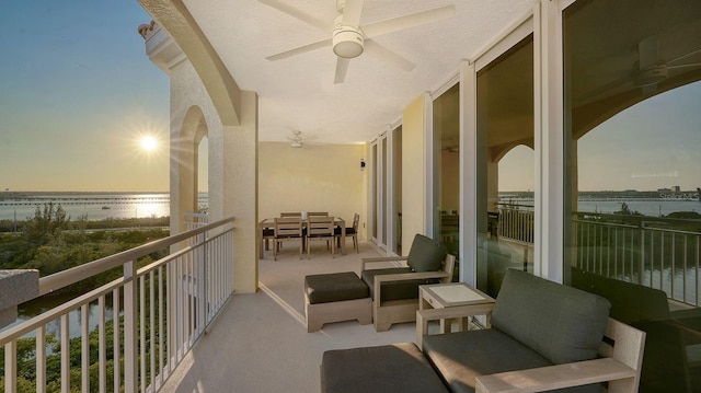 balcony featuring a ceiling fan and a water view