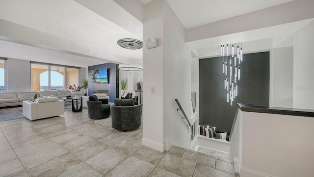 living room with light tile patterned flooring, a glass covered fireplace, and baseboards