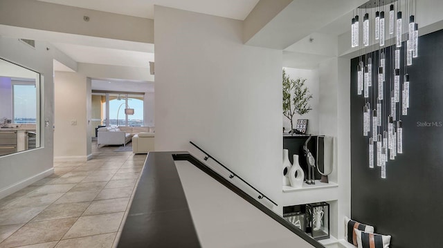 hallway with baseboards, an upstairs landing, visible vents, and light tile patterned flooring