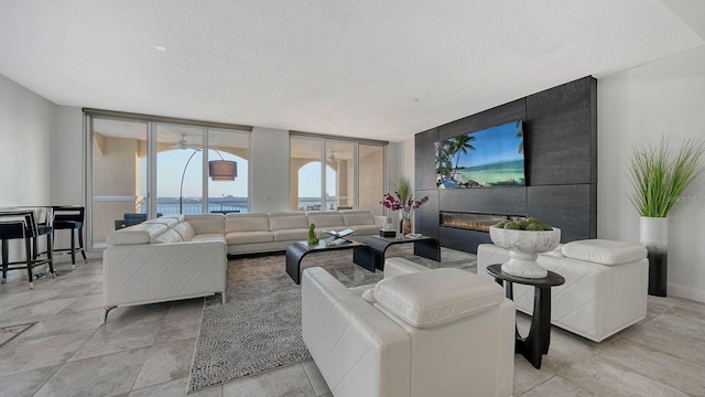 living area featuring floor to ceiling windows, a fireplace, baseboards, and a textured ceiling