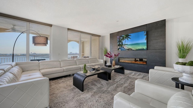 living room featuring expansive windows, a water view, a large fireplace, and a textured ceiling