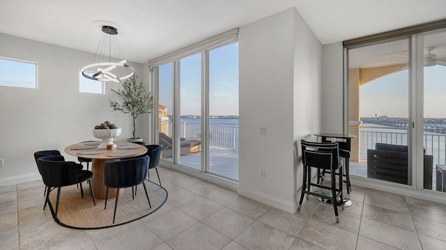 dining space featuring light tile patterned floors, a chandelier, a wall of windows, and baseboards