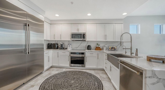 kitchen featuring a sink, a peninsula, backsplash, and stainless steel appliances